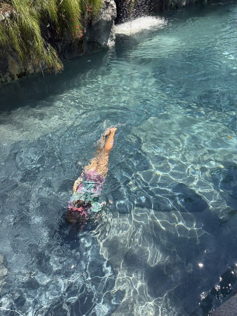A child diving through the crystal-clear water of the hotel's natural rock-cut cave pool