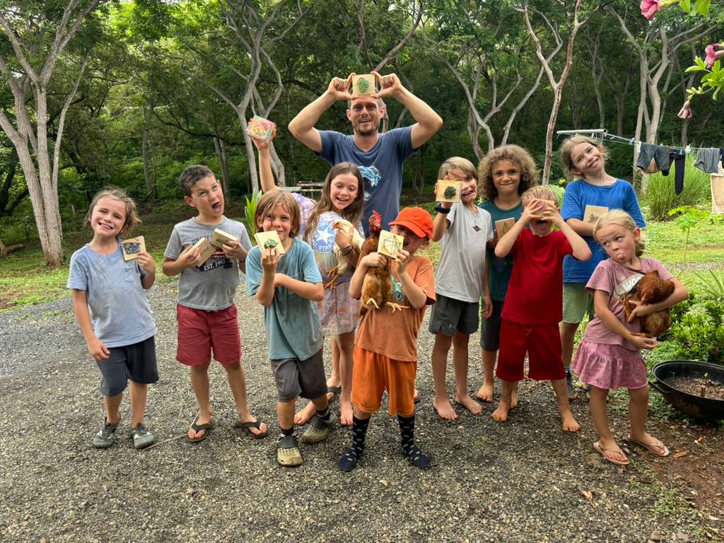 A big group of children holding their hand-made nature crafts and a hen at a local school